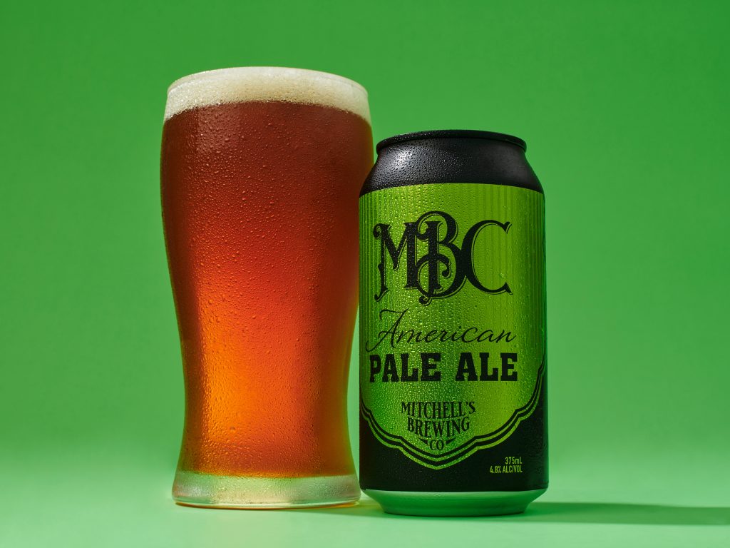 Product photography image of green can of beer next to a poured glass of beer on a green background
